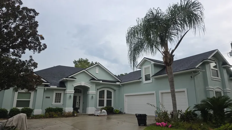 Sage stucco home with white trim after an exterior repaint