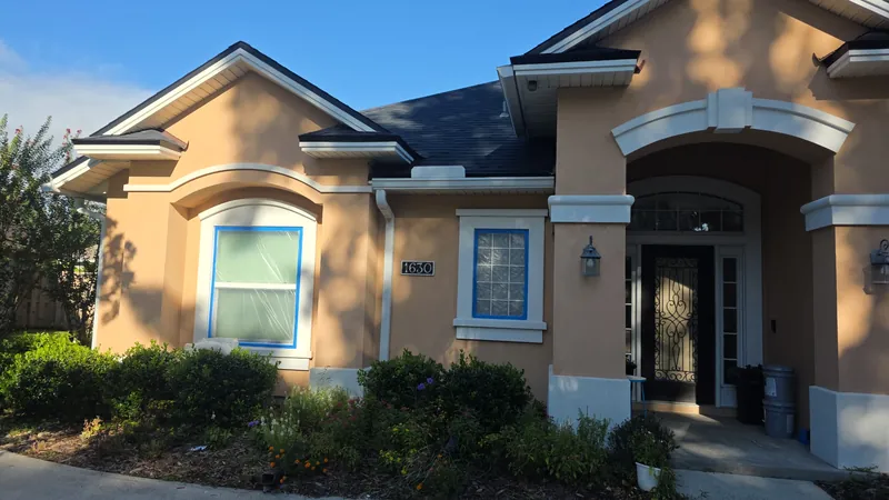 Exterior repaint in progress, with windows masked and protected