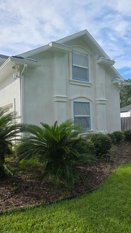 Two-story stucco home with fresh body color and white window trim