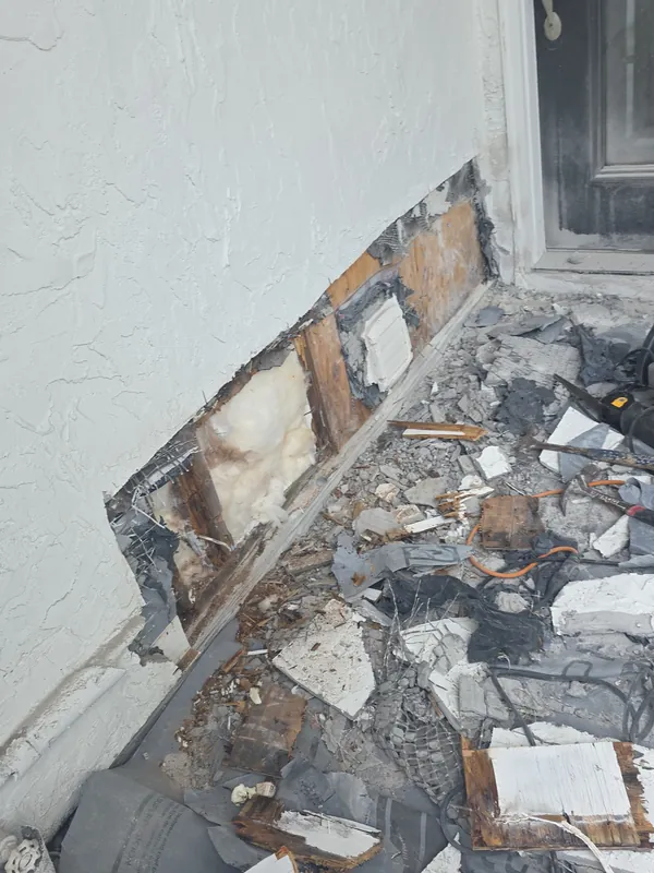 Entry wall before: damaged stucco cut out for repair